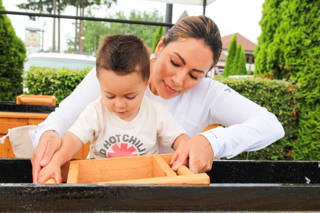 Yessi Dunegan helps her 1-year-old son Jason shake a sifting box. (Photo by Luisa Loi)