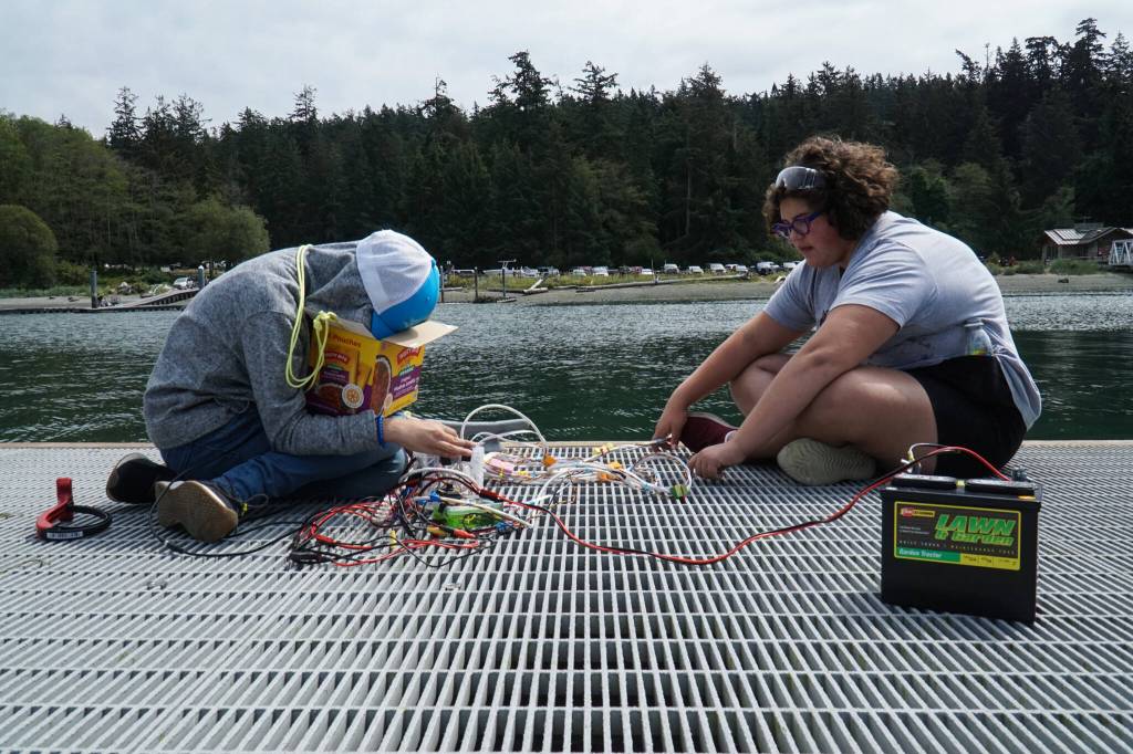 Maya Overn (left) and Pippa Place command an underwater robot at Cornet Bay on Friday. (Photo by Sam Fletcher)