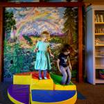Callie Edwards, 4, and Rory Dafick, 4, jump up and down in front of a rainbow mural. (Photo by David Welton)