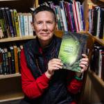 Tina Lear holds a copy of her debut novel StoryEarth Chronicles: The Sting Baby at the Kingfisher Bookstore. (Photo by Luisa Loi)