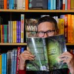 Tina Lear hides behind a copy of her debut novel StoryEarth Chronicles: The Sting Baby. (Photo by Luisa Loi)