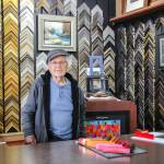 Gene Phelps stands behind the counter at Genes Art & Frame, the business he opened in 1967. (Photo by Luisa Loi)