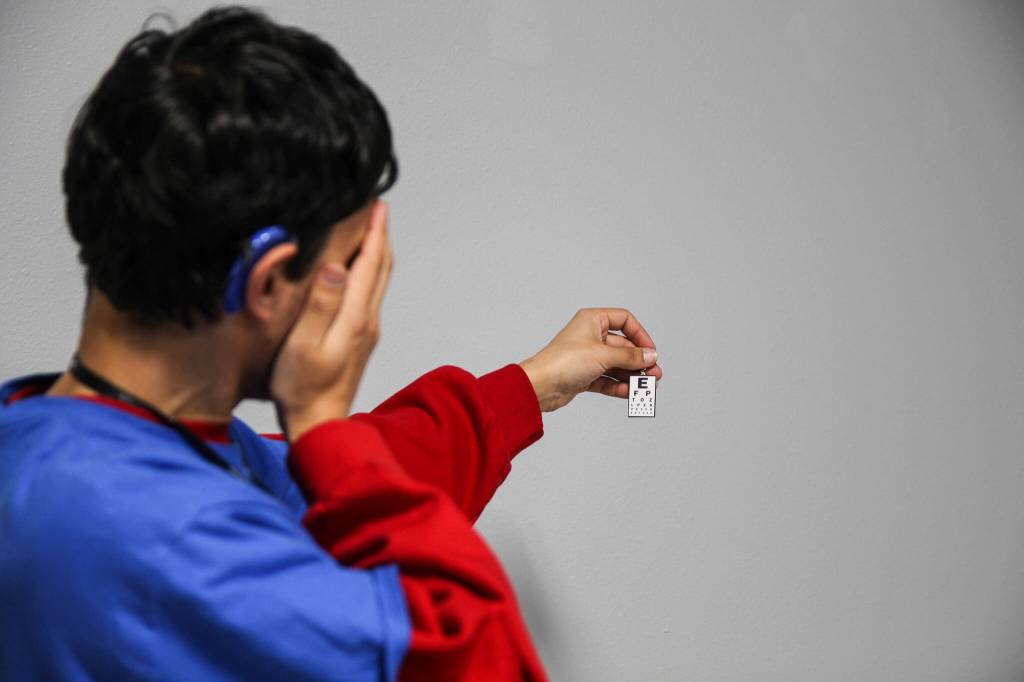 (Photo by Luisa Loi)
Roman measures his visual acuity with a Snellen eye chart earring.