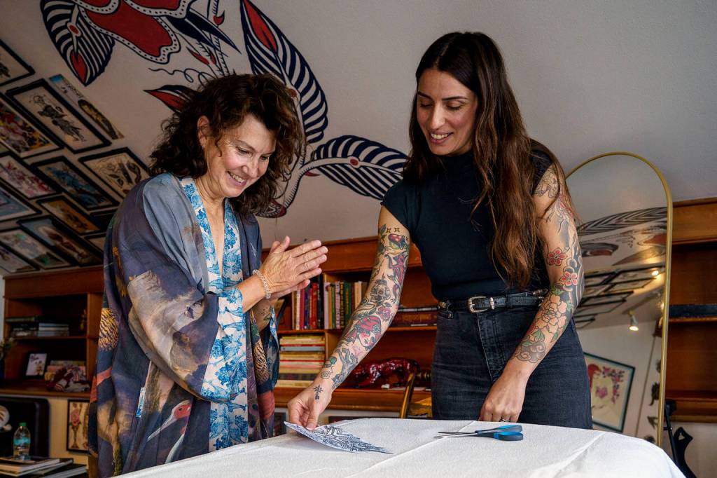 Teresa Forsyth, left, excitedly reviews the design for her tattoo with artist Renata Vignati. (Photo by David Welton)