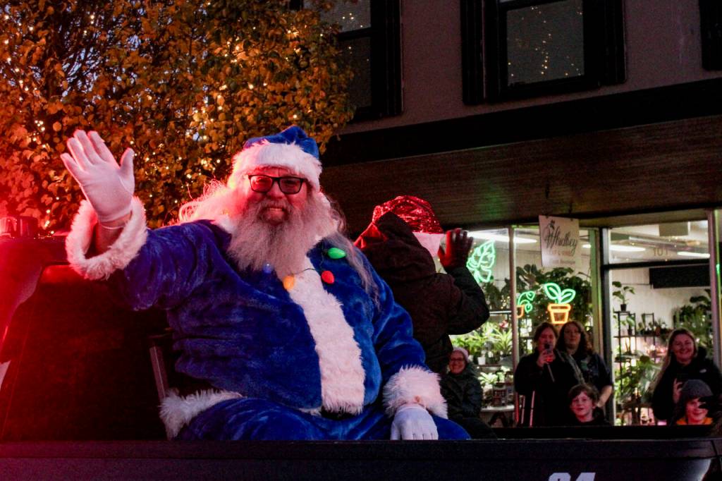 Santa takes a ride on a fire truck during the festive Oak Harbor event. In addition, all kinds of other Christmas characters marched through the towns, waving, dancing and throwing candy for the many onlookers. (Photo by Sam Fletcher)