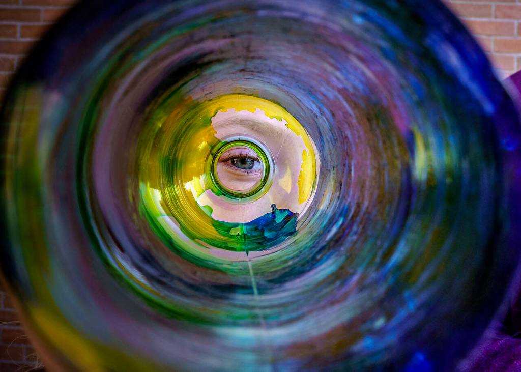 (Photo by David Welton)
Third grader River Stewart peers through the plastic water bottle she decorated with paints during an Earth Day potluck for students of the South Whidbey Alternative Learning Experience.