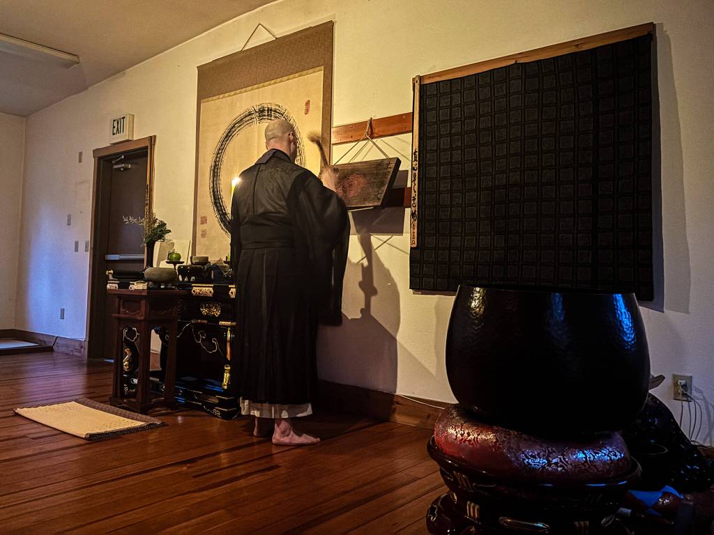 Tendo, head monk at Tahoma One Drop Zen Monastery, beats a semantron before chanting. (Photo by Sam Fletcher)