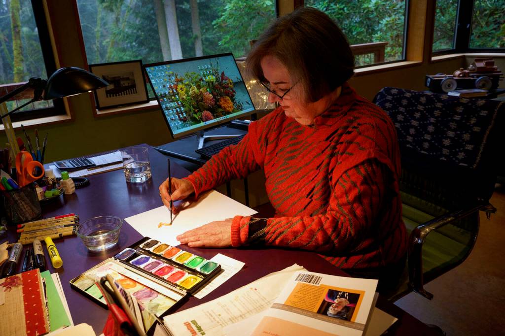 Linda Beeman paints a watercolor dahlia in her studio. (Photo by David Welton)
