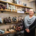 (Photo by Luisa Loi)
LeeAnna Jorgenson wears an alpaca knitted scarf while standing by a display of yarns produced by her alpacas.