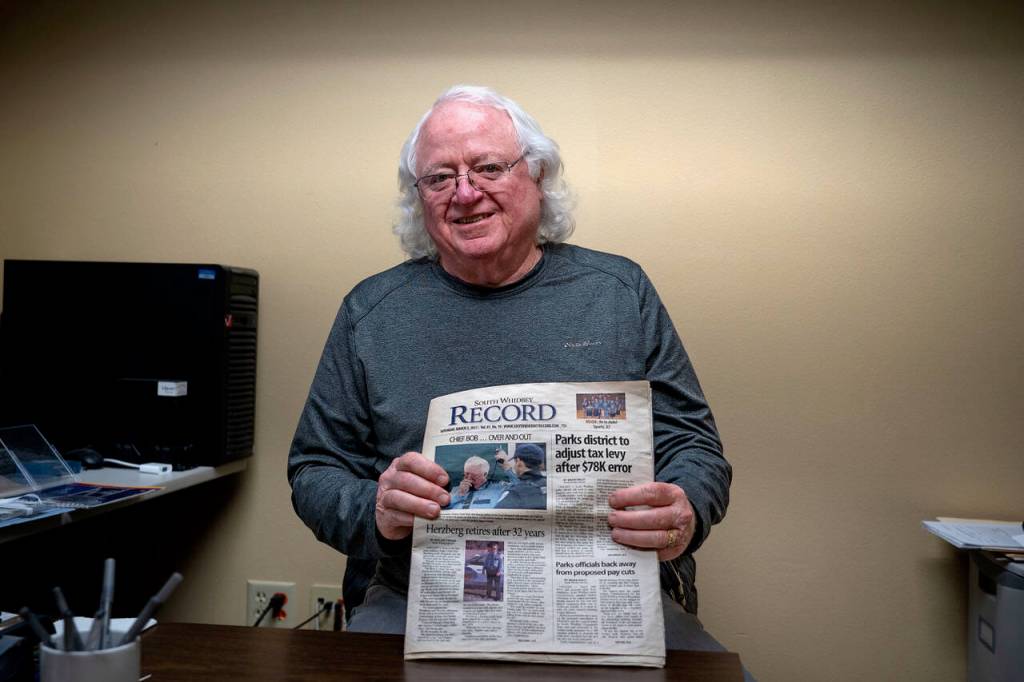 (Photo by David Welton)
Bob Herzberg holds up a 2011 copy of the <em>South Whidbey Record</em>, featuring his police chief retirement article.