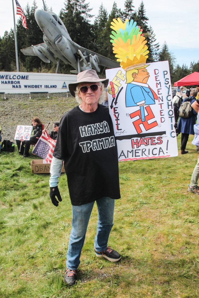 Jack Gribble, a disabled Coast Guard veteran, held a sign depicting Trump riding a swastika monowheel. (Photo by Luisa Loi)