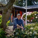 Clinton Community Hall President Mike Gerhardt poses near an old nurse log that members of the South Whidbey Garden Club dragged uphill in the late 1960s. (Photo by David Welton)