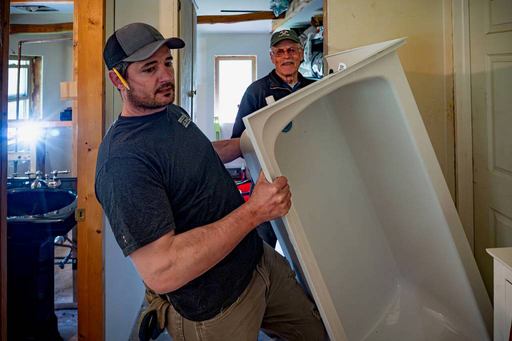 Bruce Schwager, a captain for Keira Kingfisher home project, help with Isaac Leitz wrestle a tub.