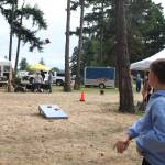 A kid plays beanbag toss at the farmers market (Photo by Marina Blatt)