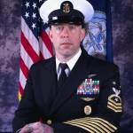 (Photo by Navy) Faulises headshot, featuring a traditional rose tattoo on his hand.