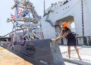 Mattie Hanley, wife of DARPA director Stephen Winchell, smashes a bottle to christen the USX-1 Defiant, first-of-its kind autonomous naval ship, at Everett Ship Repair on Monday, Aug. 11, 2025 in Everett, Washington. (Olivia Vanni / The Herald)