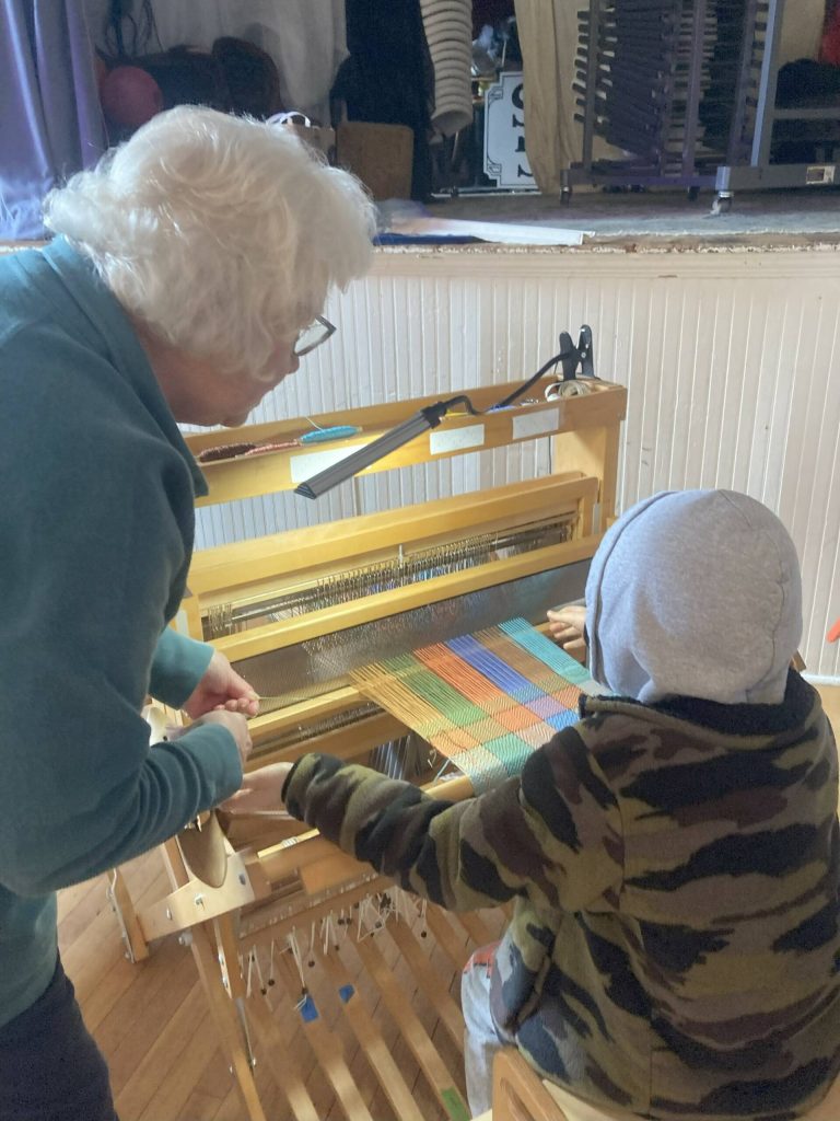 (Photo by Katrina Morse) Learning to weave at A Little Fiber Fest: From Sheep to Cloth event hosted by the Langley library.
