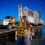 Photo by David Welton
Tevon Dubois and Chanel Jost in October 2023, posing in front of their house as it is loaded onto a truck at a Possession Point dock.