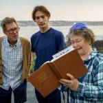 (Photos by David Welton) Father and son, Aaron and Hillel Coates, peer over Susan Bennets shoulder as she recites the order of the shofars blasts from the Siddur, a Jewish prayer book.