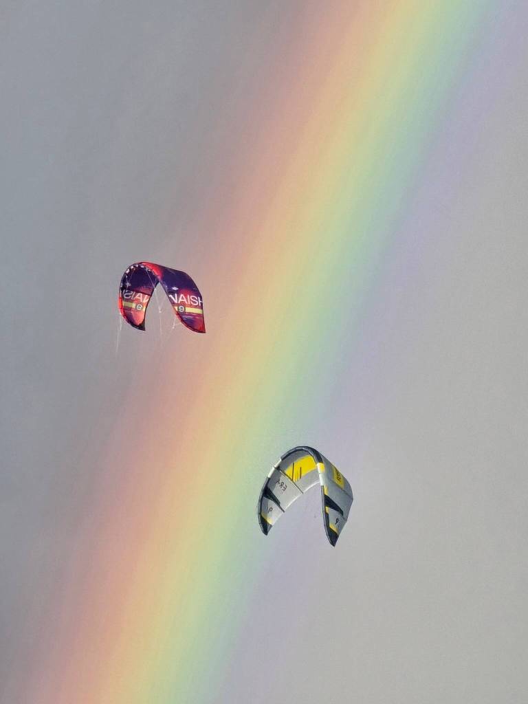 (Photo by Nichol Redfearin) Kites float in front of a vibrant rainbow.