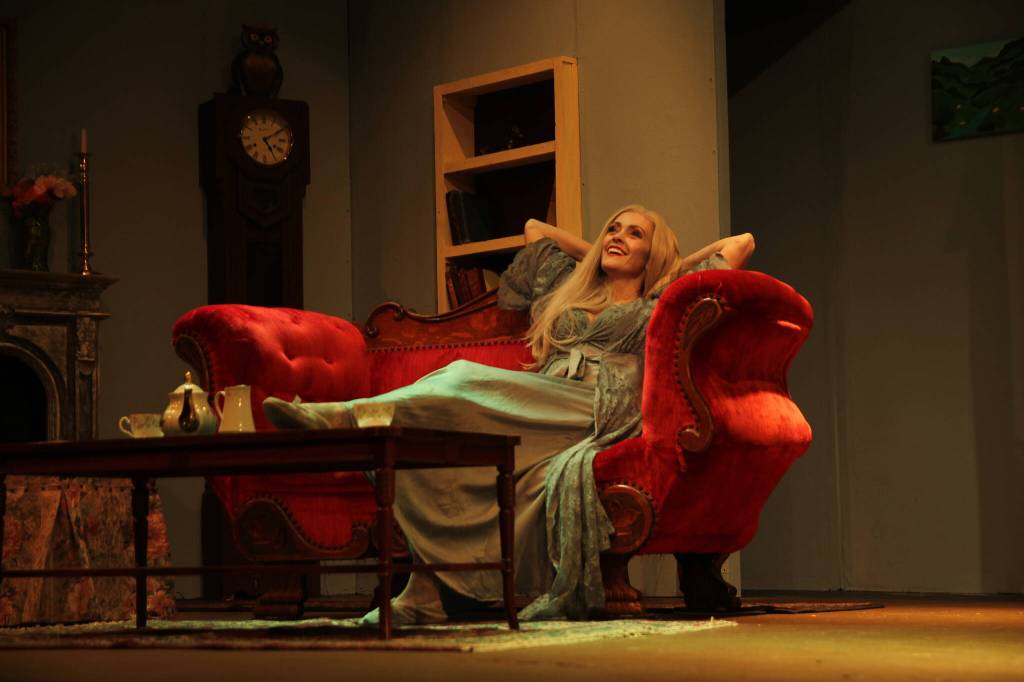 Abby Thuet, playing Elvira, lounges casually on a sofa. (Photo by Marina Blatt)