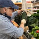 (Photo provided by Good Cheer) A Good Cheer volunteer sorts some leafy greens in the food bank.