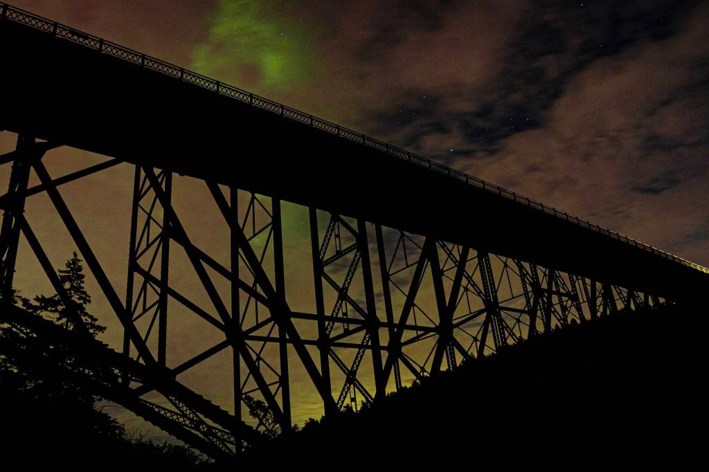 Photo by Randy Heiserman at Deception Pass. The aurora borealis peeps in between the clouds.