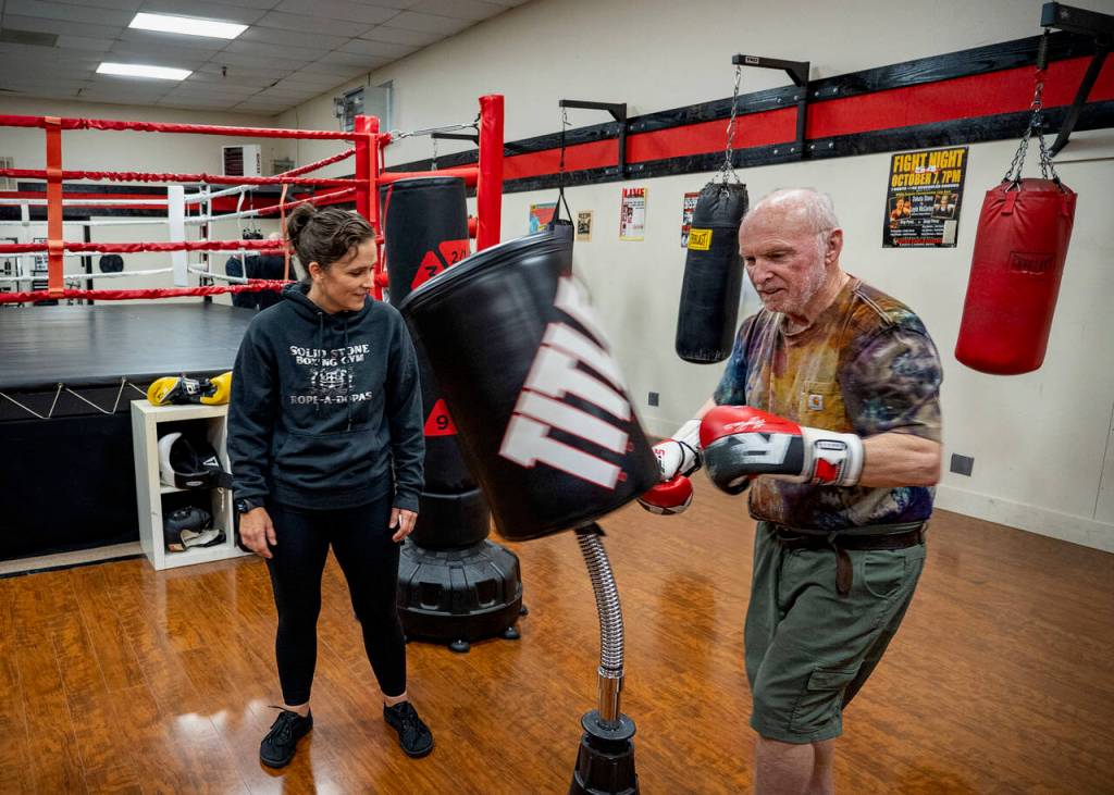 Wil Kerns warms up by punching the bag while Lauren Stone looks on. (Photo by David Welton)
