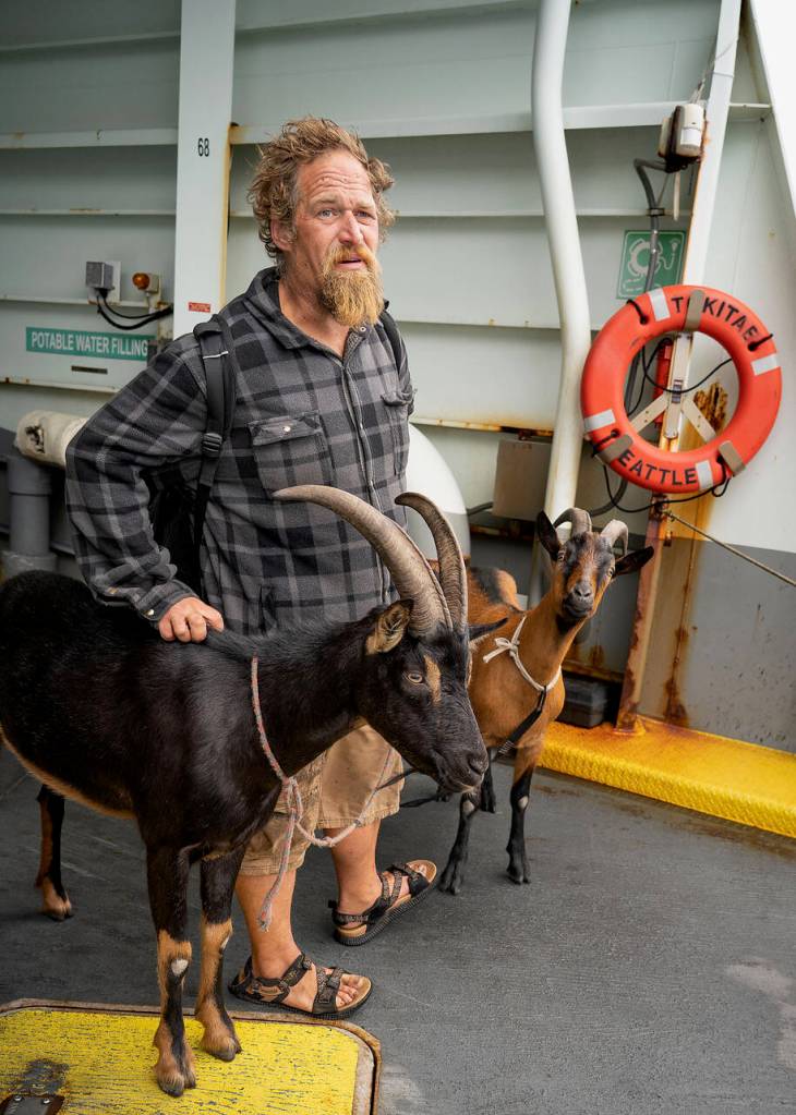 (Photo by David Welton) Mark Cole takes the ferry with his two goat sidekicks.