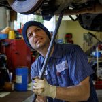 (Photo by David Welton) Senior Technician Mark Glass gets under a car to work on it.