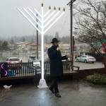 (Photo provided by the Chabad Jewish Center of Skagit County) The Skagit County Chabad Rabbi Shmuli Silver speaks in front of the giant menorah in last years celebration, barely reaching the branches of the giant menorah.