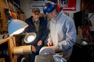 (Photo by David Welton) Don Wodjenski, left, shows Nathan Welton how to turn a wooden bowl on his lathe. Wodjenski is open to teaching more people who are interested in learning.
