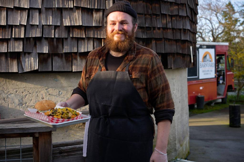 Photo by David Welton. Employee Alex Sykas carries some loaded tater tots and a sandwich to a customer.