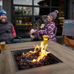 Photo by David Welton. Freeland residents Derek and Kaitlin Robinson cozy up around the firepit with their 12-year-old pitbull mix, Aggie, at The Barnyard.