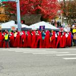 Photo by Greg Jensen. A peacekeeper stands out in their neon vest as they protect a group of red-cloaked activists.