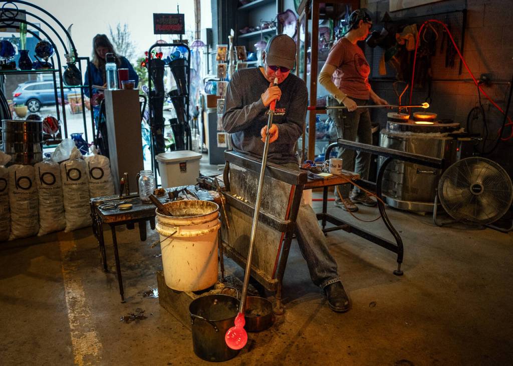 Photo by David Welton. Callahan McVay develops the shape of sea glass floats using snipping tools and heat from the ever-flowing furnace inside Callahans Firehouse Studio in Langley.