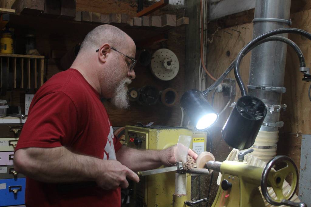 Photo by Marina Blatt. Jon McCoy carefully carves out a yarn winder. The Oak Harbor resident makes mini spinning wheels for his business, the Pocket Wheel, from his home workshop.
