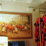 (Photo by Allyson Ballard) Yon Bureaus interior is dimly lit and tastefully decorated with other vintage finds, like this painting, salvaged from a hoarders house in Bellevue and repurposed as a sign.