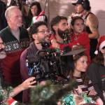Photo by Allyson Ballard
About 65 volunteer extras  including reporter Marina Blatt, pictured to the right in Christmas glasses  gathered inside a Langley Christmas Market set, where tables overflowed with holiday décor, cookies and Christmas-themed gifts for sale, to take part in a Christmas movie.